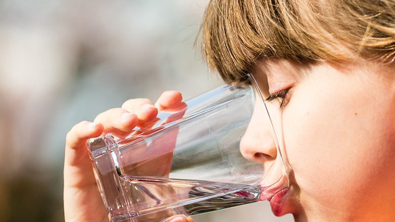 barn drikker vann fra glass